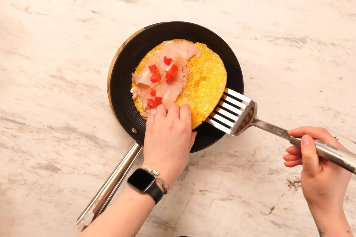 Crispy Halloumi Egg Wrap (High Protein, Low Carb) 7 Adding ham and toppings to halloumi egg wrap in skillet