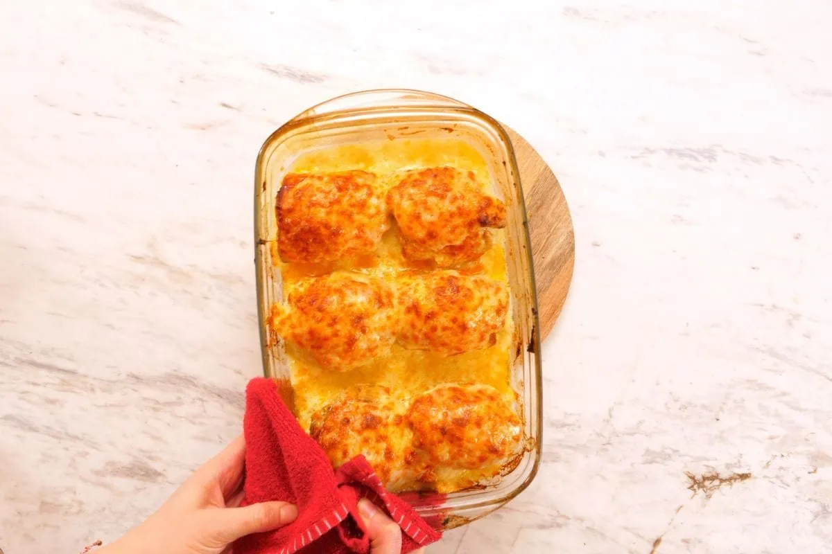 Famous Chicken Breast Rolls 11 Removing cheesy chicken breast rolls from oven in baking dish
Close up of cheesy stuffed chicken breast rolls with melted topping