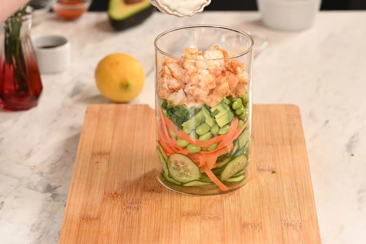 High-Protein Sushi Roll Salad (Spicy Shrimp Jar Salad) 7 Adding cooked shrimp to sushi roll salad ingredients in glass jar