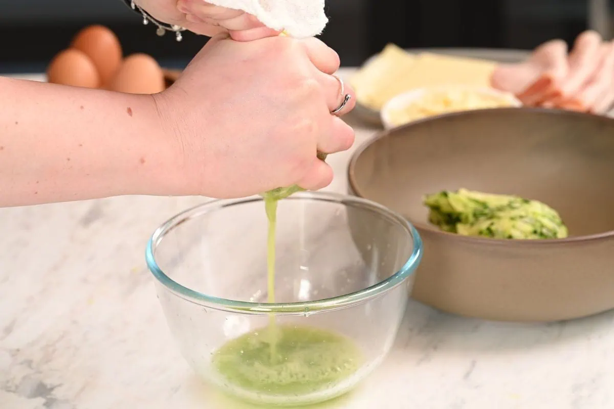 Zucchini Ham and Cheese Roll 5 Squeezing grated zucchini in a towel to remove moisture for zucchini ham and cheese roll recipe