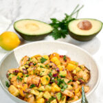 High-protein shrimp mango avocado salad with juicy shrimp, fresh mango, creamy avocado, red onion, and parsley in a bowl.