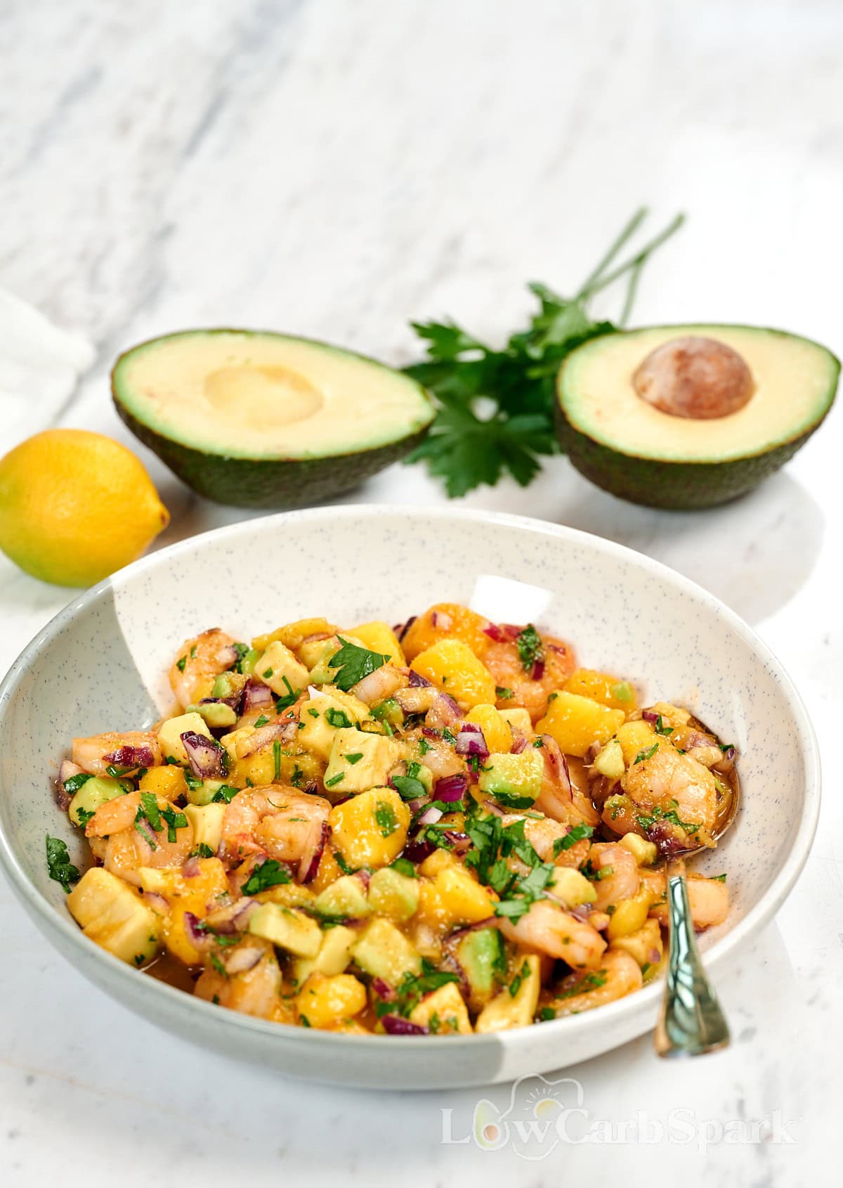 High-Protein Shrimp Mango Avocado Salad 1 High-protein shrimp mango avocado salad with juicy shrimp, fresh mango, creamy avocado, red onion, and parsley in a bowl.