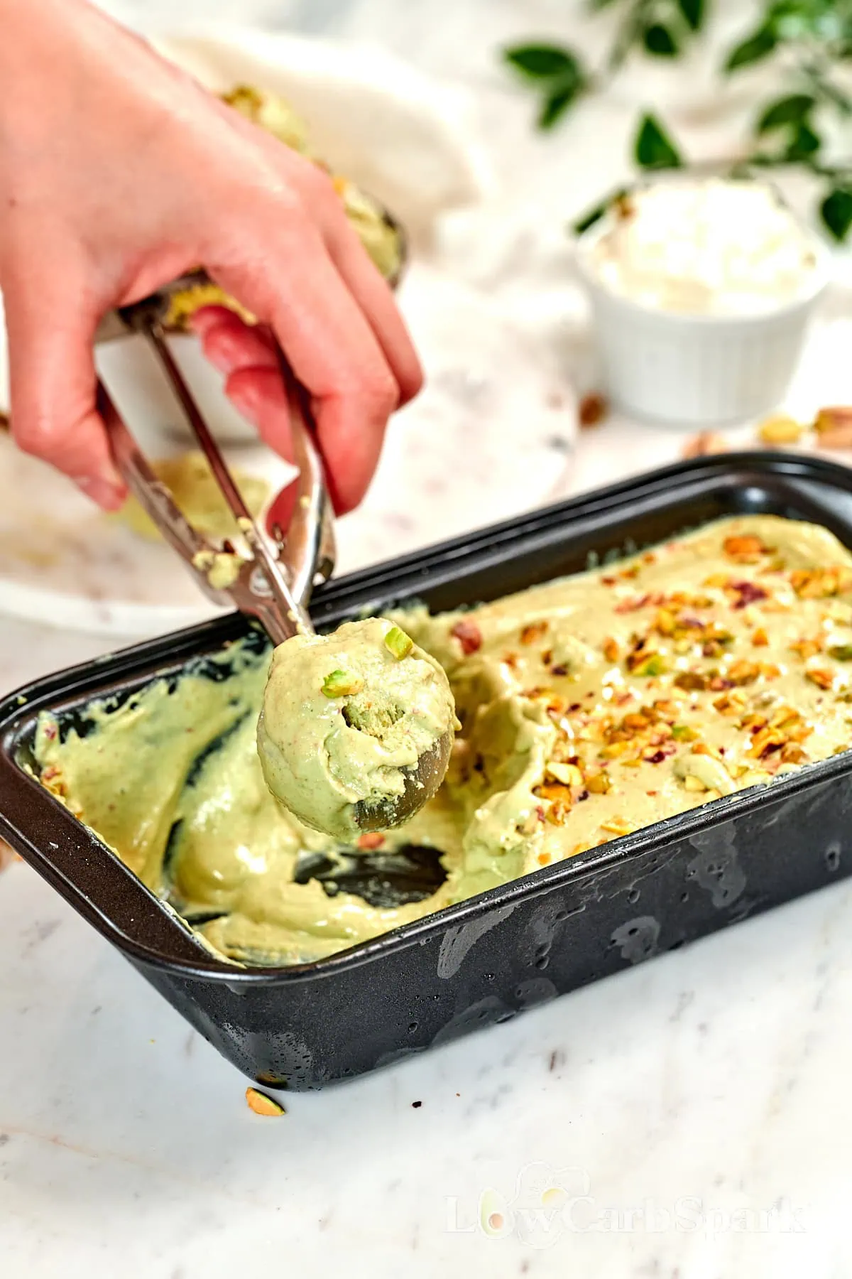 4-Ingredient Pistachio Cottage Cheese Ice Cream 2 Scooping homemade pistachio cottage cheese ice cream from a loaf pan, showing its smooth and creamy texture.