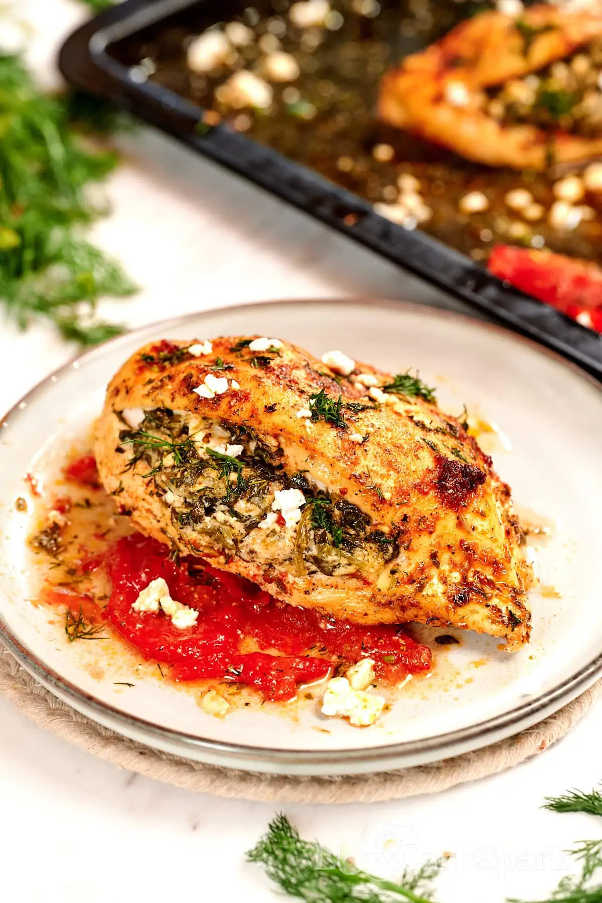 Spinach and Feta Stuffed Chicken Breast 9 Golden brown spinach and feta stuffed chicken breast plated with roasted tomatoes and crumbled feta, a healthy high protein chicken dinner.