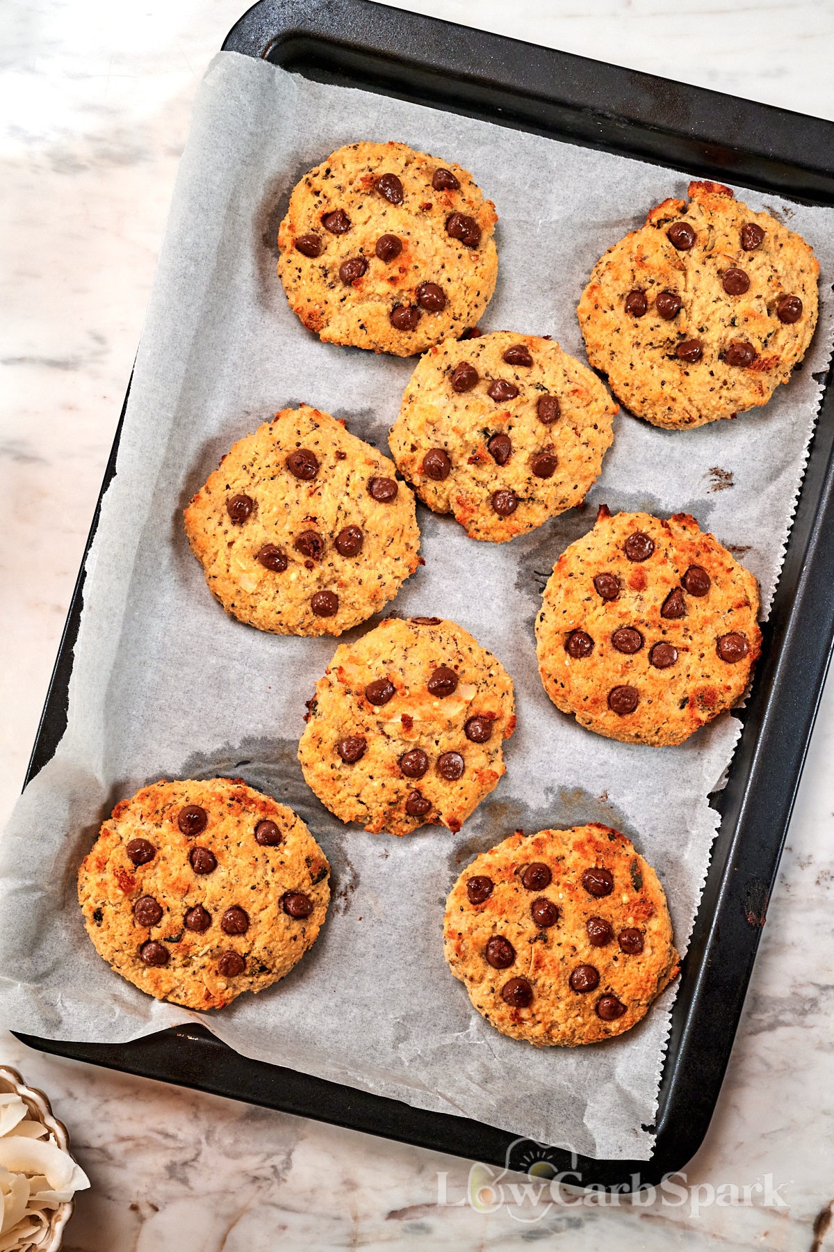 High-Protein Cottage Cheese Breakfast Cookies 2 Freshly baked High-Protein Cottage Cheese Breakfast Cookies on a parchment-lined baking sheet, made with cottage cheese, oats, chocolate chips, chia seeds, and almonds.