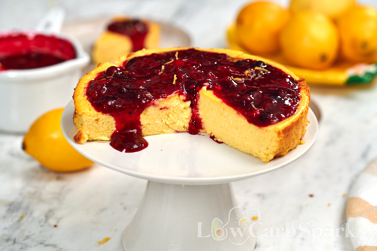 Cottage Cheese Lemon Cheesecake 13 Homemade cottage cheese lemon cheesecake with a smooth, creamy texture and mixed berry topping on a cake stand with one slice removed.
