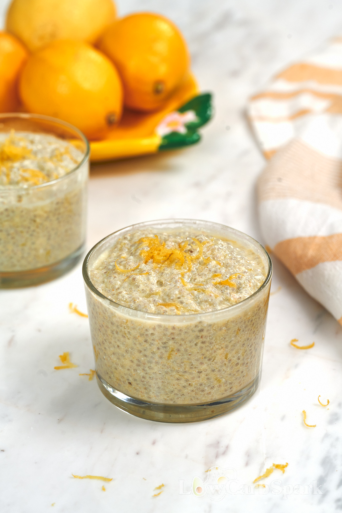 High-Protein Cottage Cheese Lemon Chia Pudding 2 Creamy high-protein cottage cheese lemon chia pudding in a glass, garnished with fresh lemon zest and served with fresh lemons.