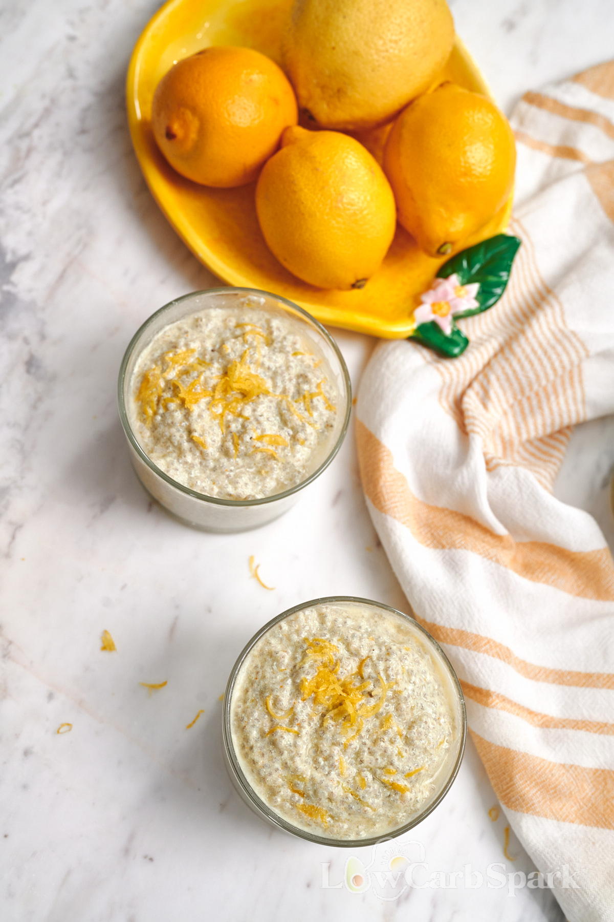 High-Protein Cottage Cheese Lemon Chia Pudding 10 Two glasses of high-protein cottage cheese lemon chia pudding topped with lemon zest on a marble countertop.