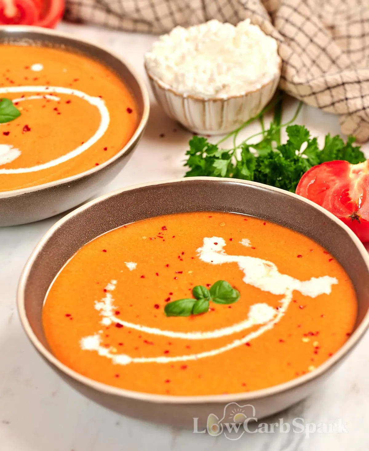 High-Protein Tomato Soup with Cottage Cheese 11 Close-up of creamy roasted tomato soup with cottage cheese, finished with a swirl of cream, fresh basil, and red pepper flakes for extra flavor.