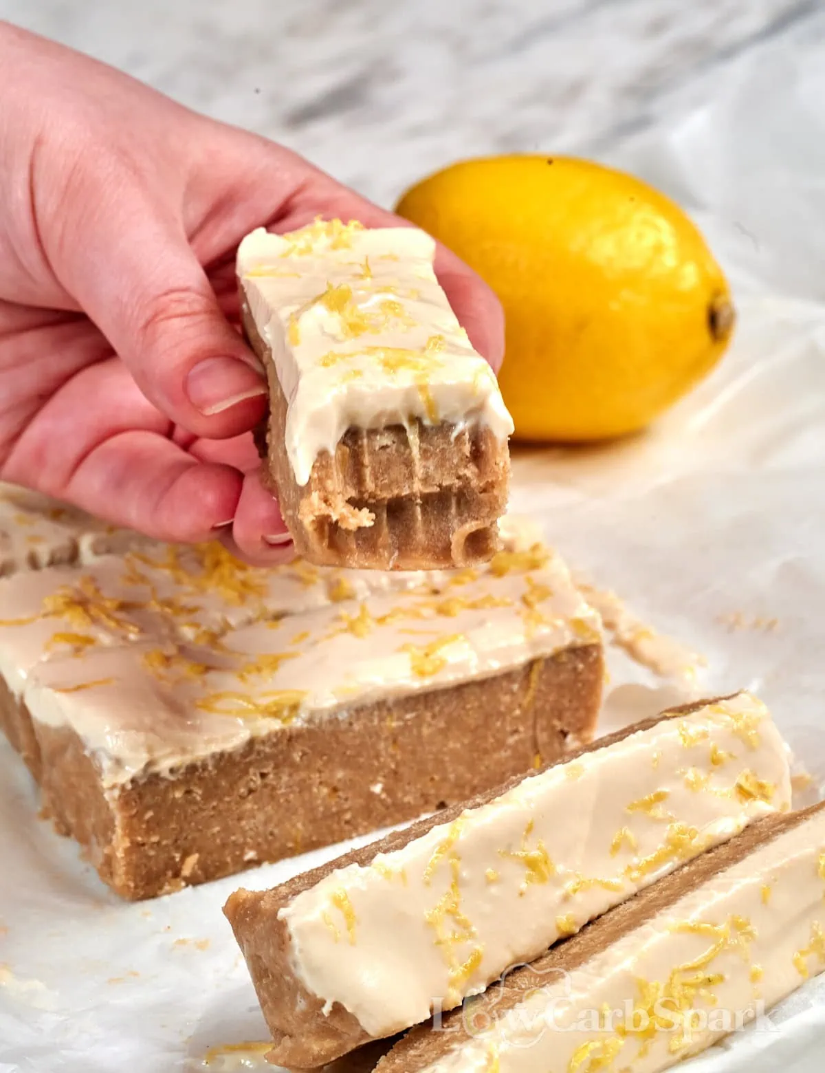 Lemon Cottage Cheese Protein Bars 13 Close-up of a frosted lemon protein bar with a creamy cottage cheese topping and bright lemon zest.