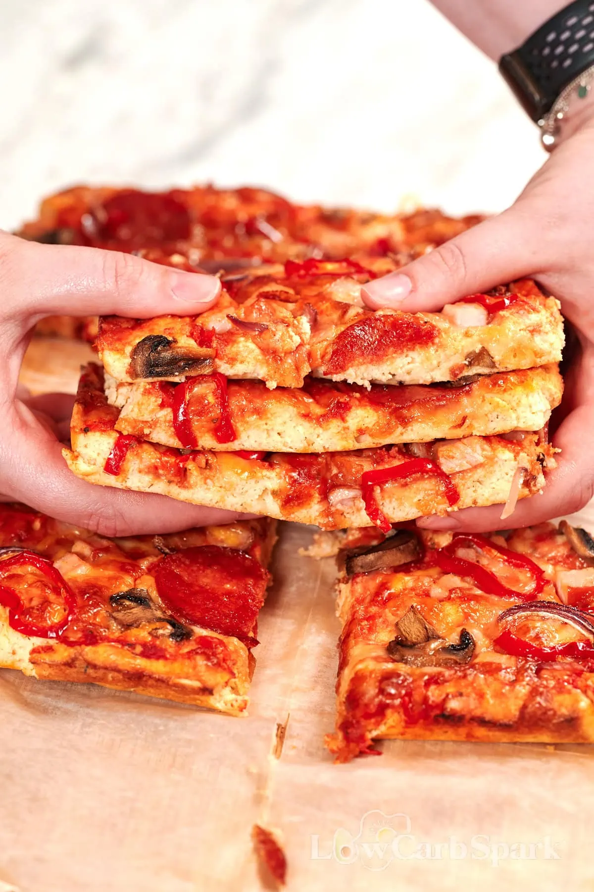 Sheet Pan Cottage Cheese Pizza 2 Hands pulling apart stacked slices of sheet pan cottage cheese pizza topped with pepperoni, mushrooms, red onion, and peppers.