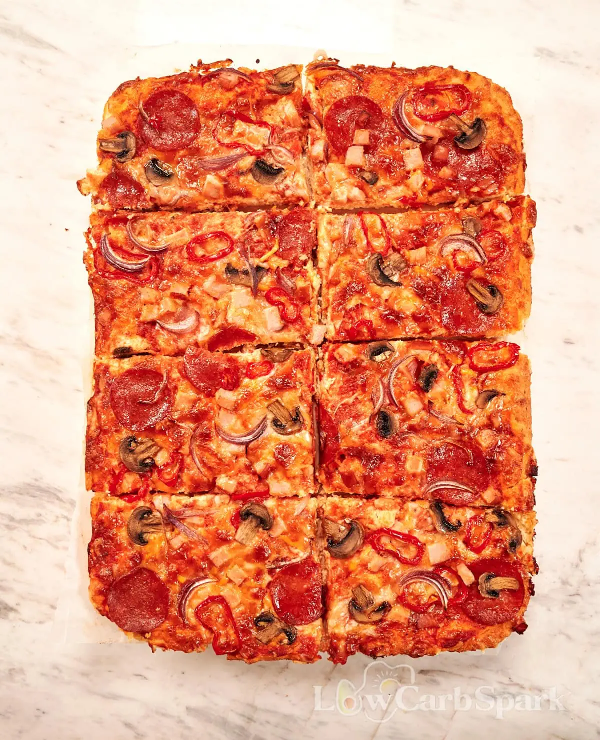 Sheet Pan Cottage Cheese Pizza 7 Overhead view of sheet pan cottage cheese pizza cut into squares with pepperoni, mushrooms, red onion, peppers, and melted cheese.