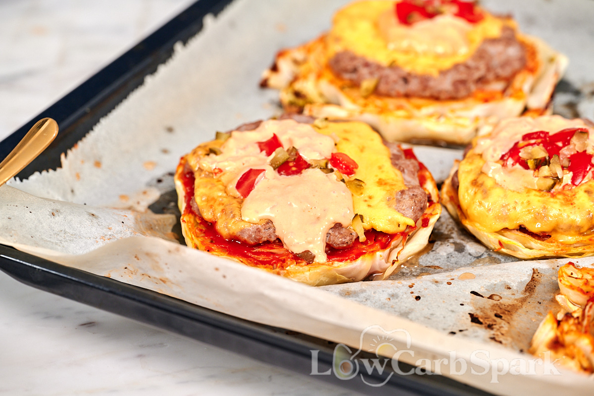 Cabbage Cheeseburgers 13 Baked cabbage cheeseburgers on a parchment lined sheet pan with melted cheese and creamy burger sauce.