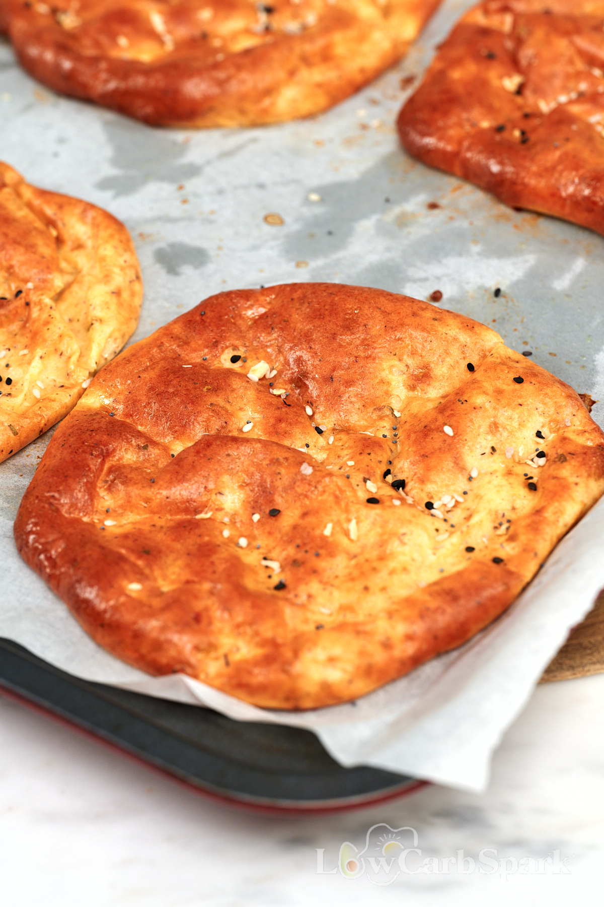 Cottage Cheese Psyllium Buns 2 Freshly baked cottage cheese psyllium buns topped with everything bagel seasoning on a parchment lined baking sheet.