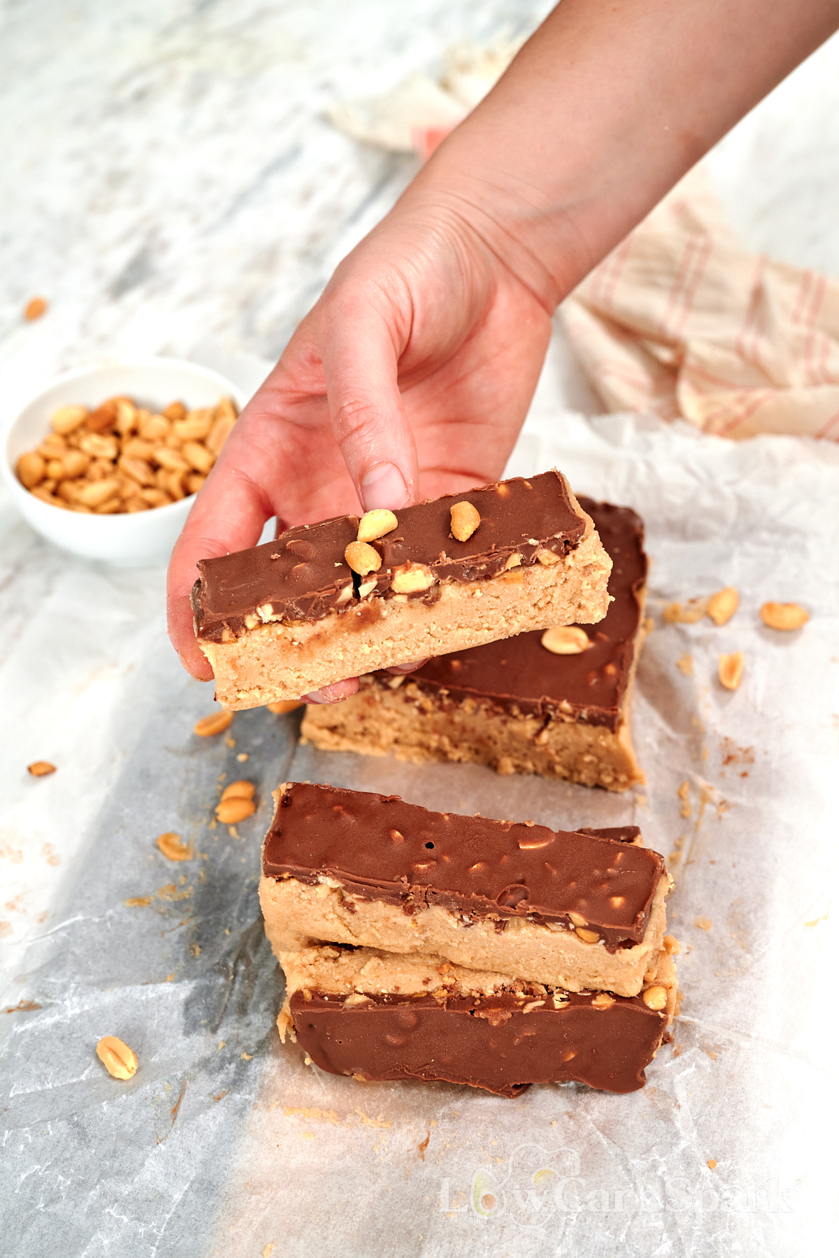 Cottage Cheese Snickers Bars 15 Hand holding a high protein cottage cheese Snickers bar topped with chocolate and chopped peanuts.