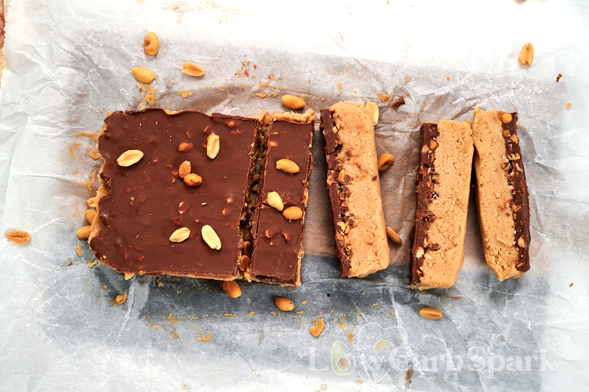 Cottage Cheese Snickers Bars 16 Sliced high protein cottage cheese Snickers bars with chocolate topping and peanuts arranged on parchment paper.