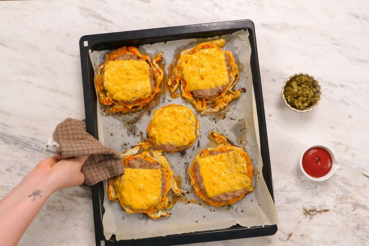 Cabbage Cheeseburgers 11 Baked cabbage cheeseburgers with melted cheddar cheese on a parchment lined sheet pan.