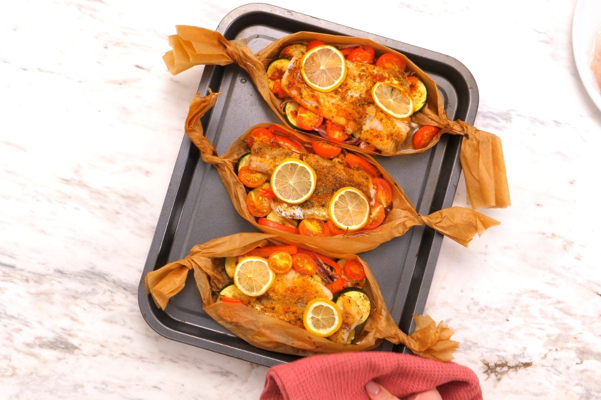 Mediterranean Baked Fish Boats 8 Baked Mediterranean fish boats with seasoned white fish, roasted vegetables, cherry tomatoes, and lemon slices.