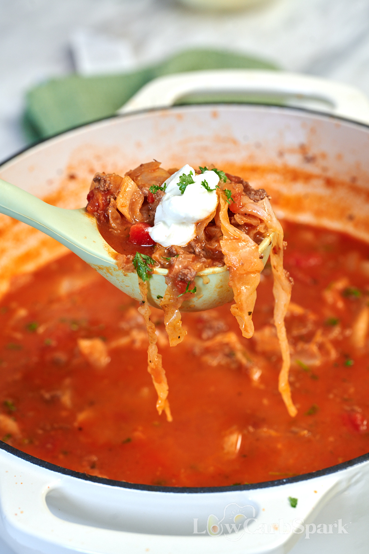 Ladle of cabbage lasagna soup with ground beef, tender cabbage, cottage cheese, and fresh parsley.
