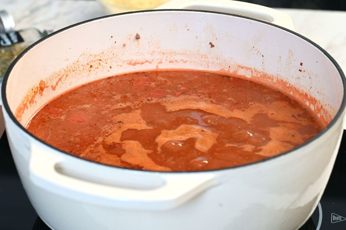 High-Protein Cabbage Lasagna Soup 9 Tomato broth simmering with seasoned ground beef in a Dutch oven for cabbage lasagna soup.