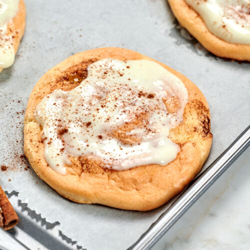 Cloud Cinnamon Rolls with Cottage Cheese 16 Cloud cinnamon roll with cottage cheese topped with creamy frosting and a sprinkle of cinnamon on a baking tray.