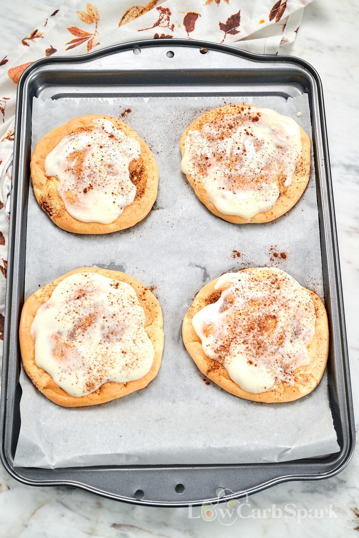 Cloud Cinnamon Rolls with Cottage Cheese 15 Four cloud cinnamon rolls with cottage cheese topped with creamy frosting and cinnamon on a parchment-lined baking tray.